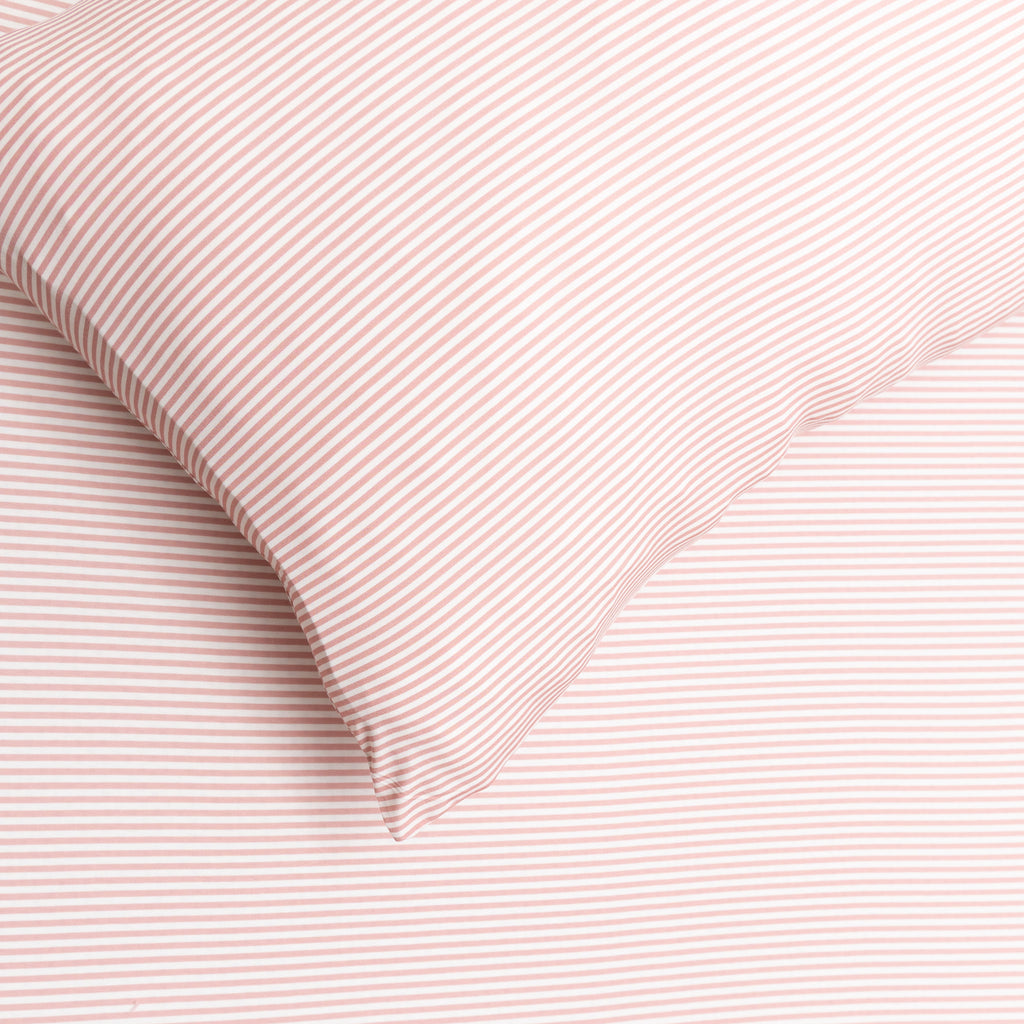 Close-up of pink textured fabric with a pillow corner.