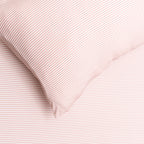 Close-up of pink textured fabric with a pillow corner.
