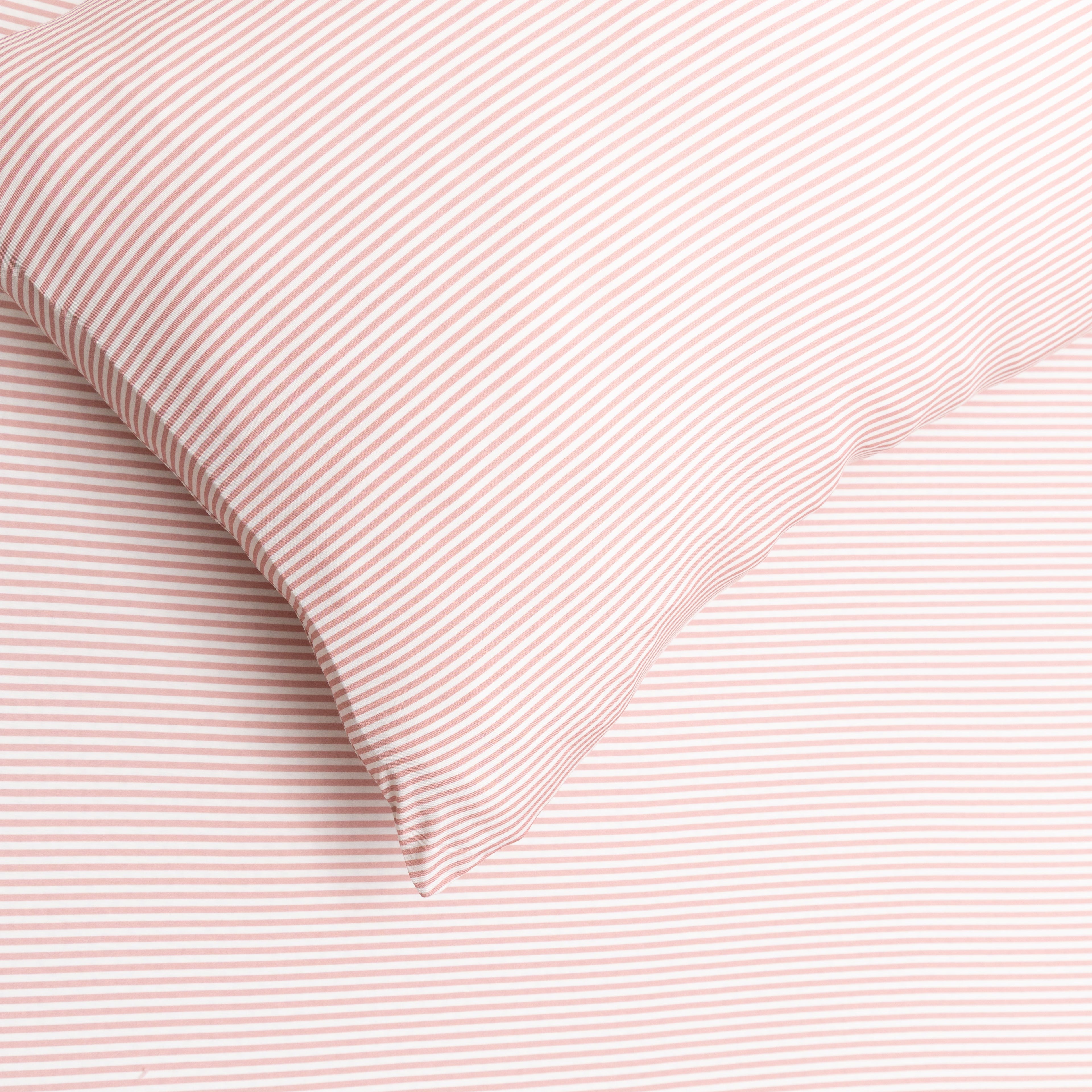 Close-up of pink textured fabric with a pillow corner.