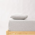 Minimalist bed with wooden frame and light gray mattress and pillow on a white background