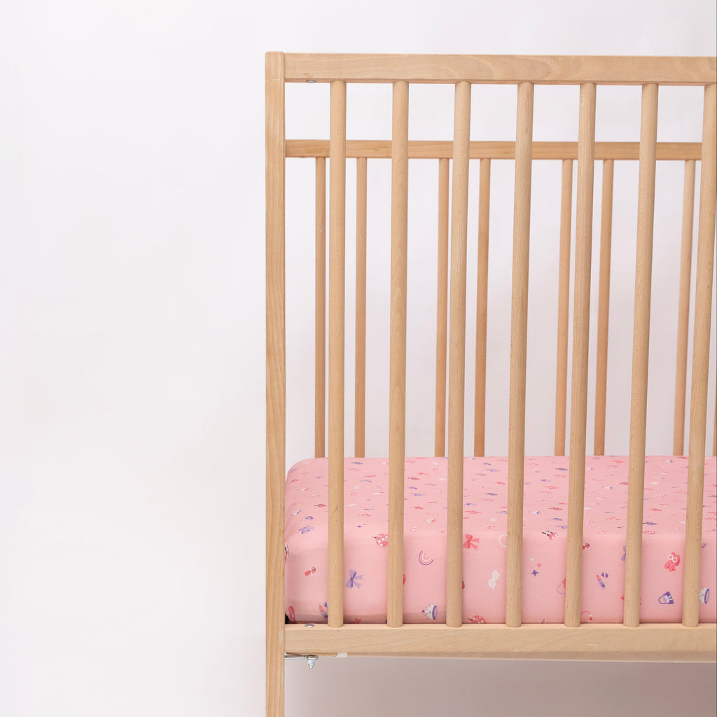 Wooden crib with pink sheets on a white background