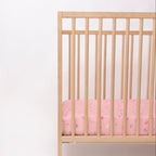 Wooden crib with pink sheets on a white background