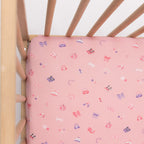 Wooden crib with pink sheets on a white background