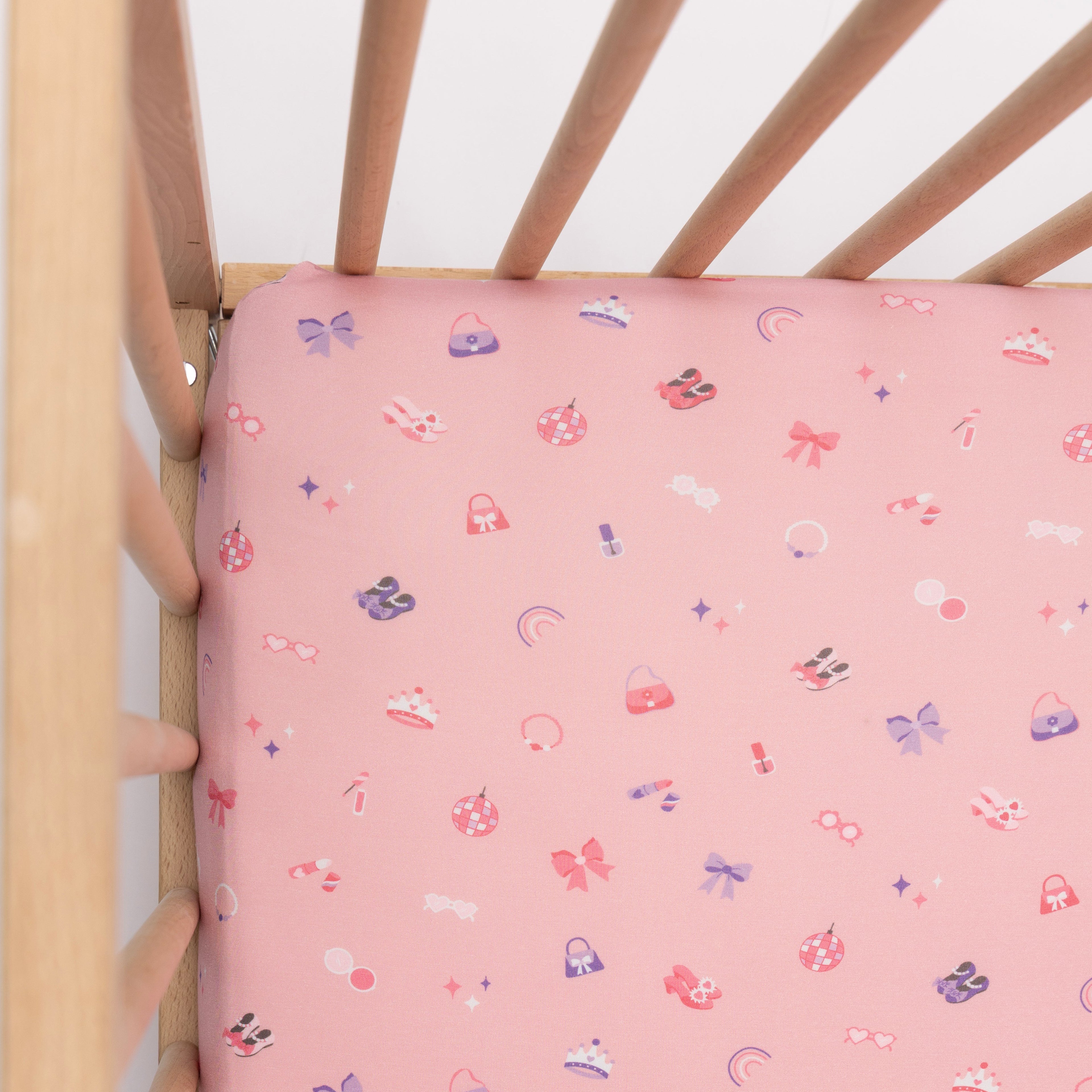 Wooden crib with pink sheets on a white background