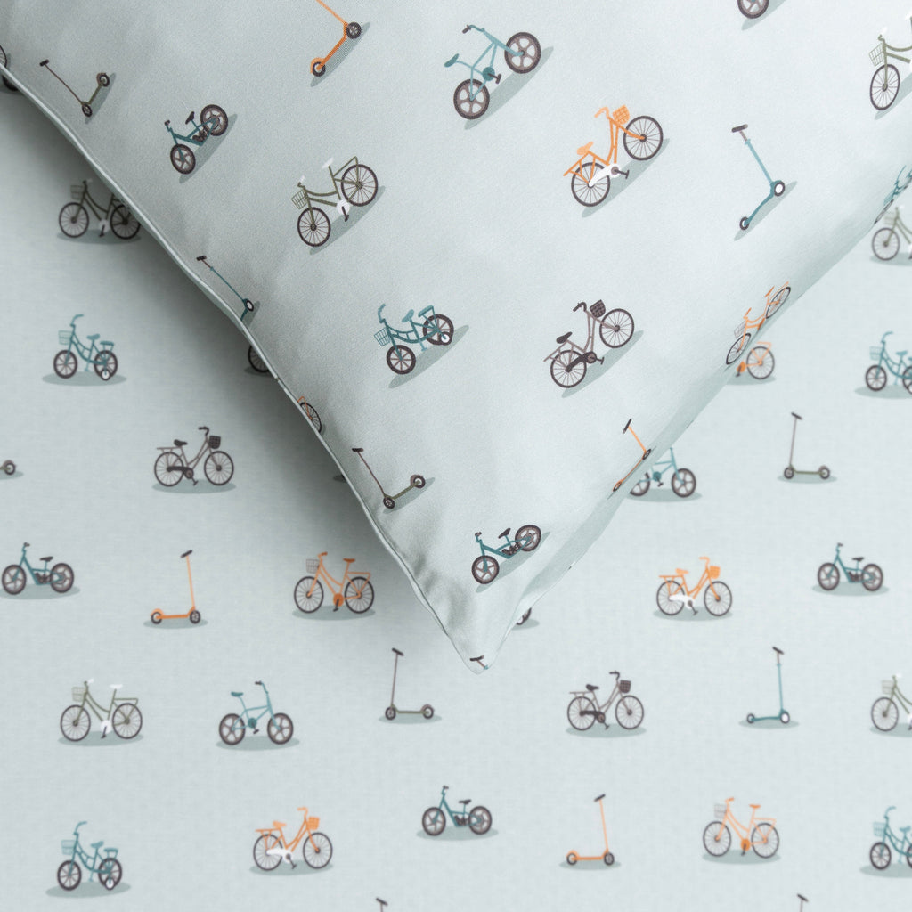 Fabric with small bike and scooter patterns on a light blue background
