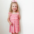 Young girl wearing a pink dress with girly patterns on a white background