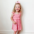 Young girl wearing a pink dress with girly patterns on a white background