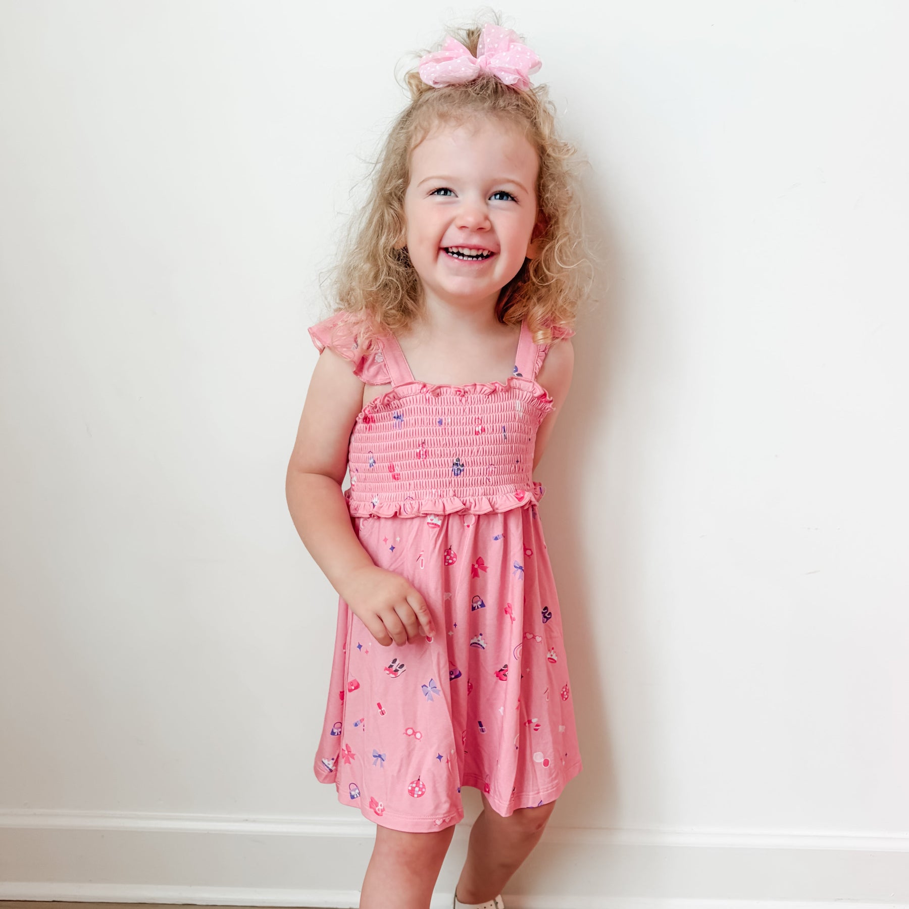 Young girl wearing a pink dress with girly patterns on a white background