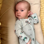 Baby in a vehicle-patterned onesie lying on a beige surface