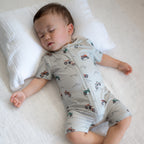 Baby wearing a light gray onesie with vehicle patterns while sleeping