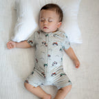 Baby wearing a light gray onesie with vehicle patterns while sleeping