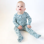 Baby wearing a blue summer-patterned onesie on a white background