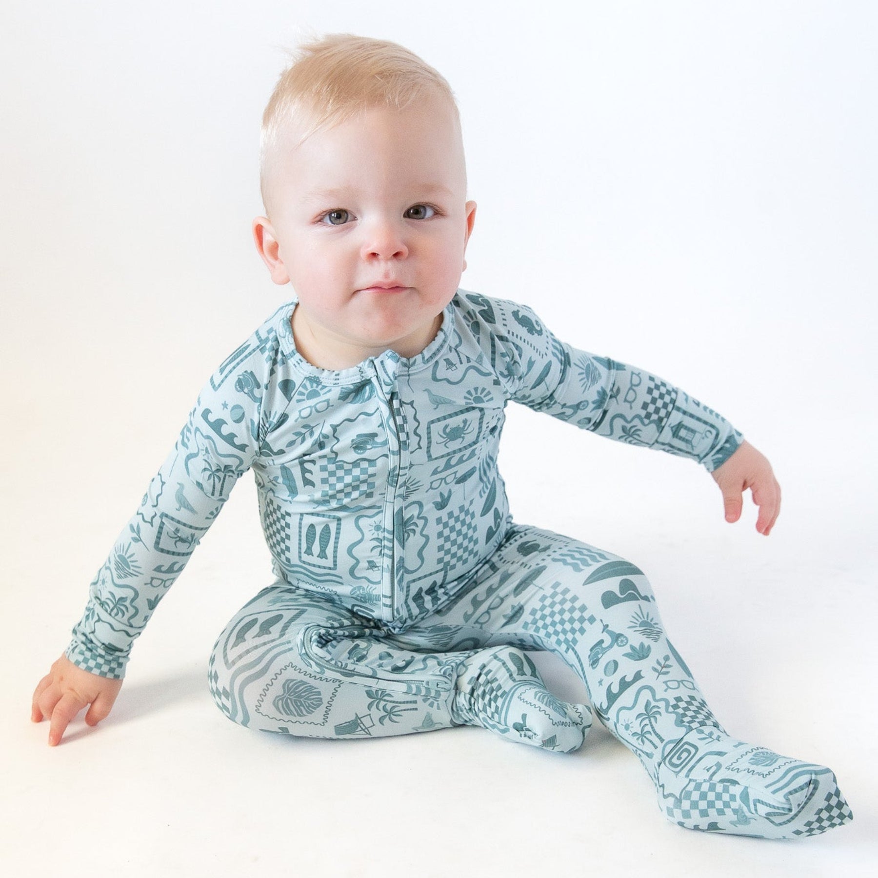 Baby wearing a blue summer-patterned onesie on a white background