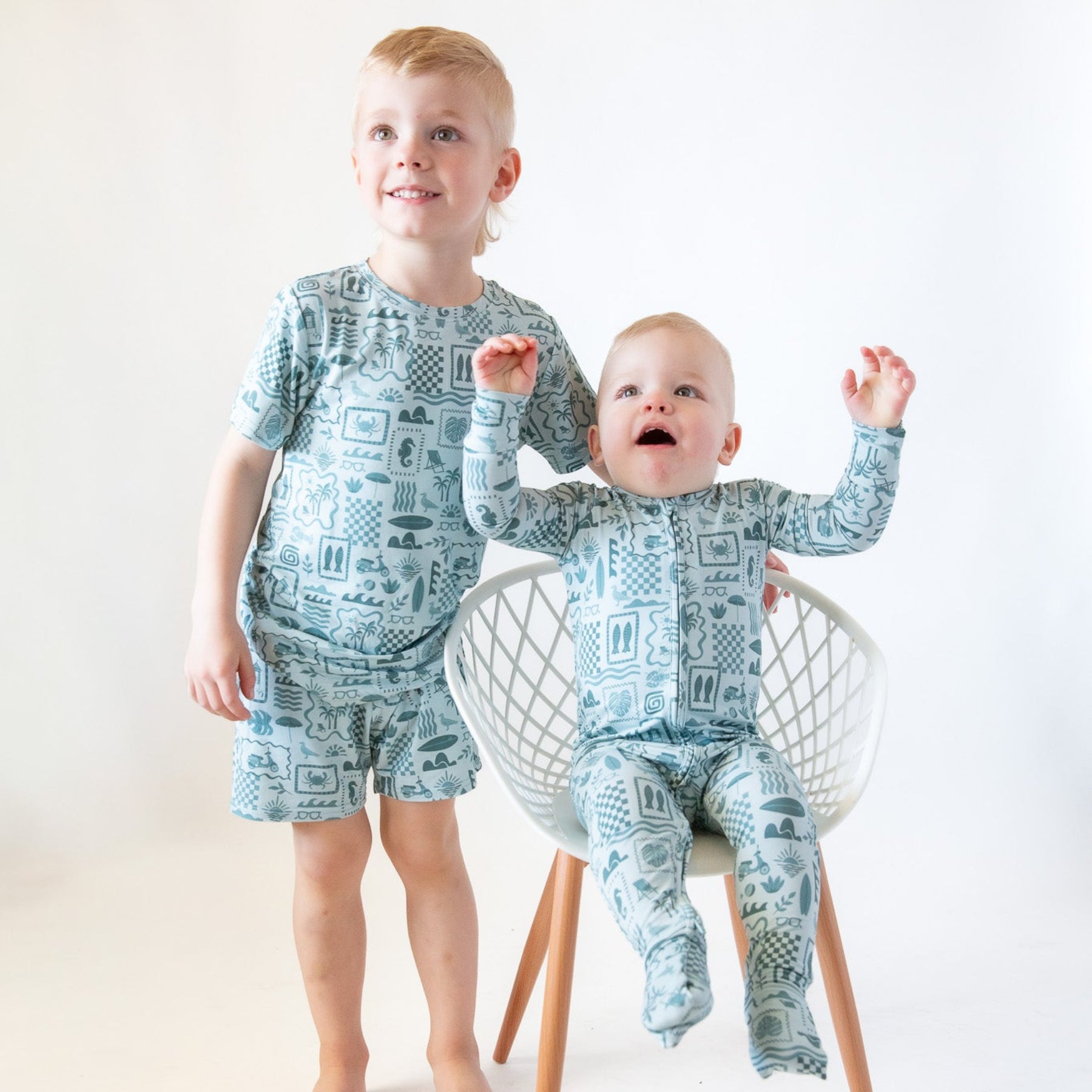 Two children wearing matching pajamas sitting on a chair against a white background