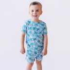 Child wearing a blue palm tree patterned pajama on a white background