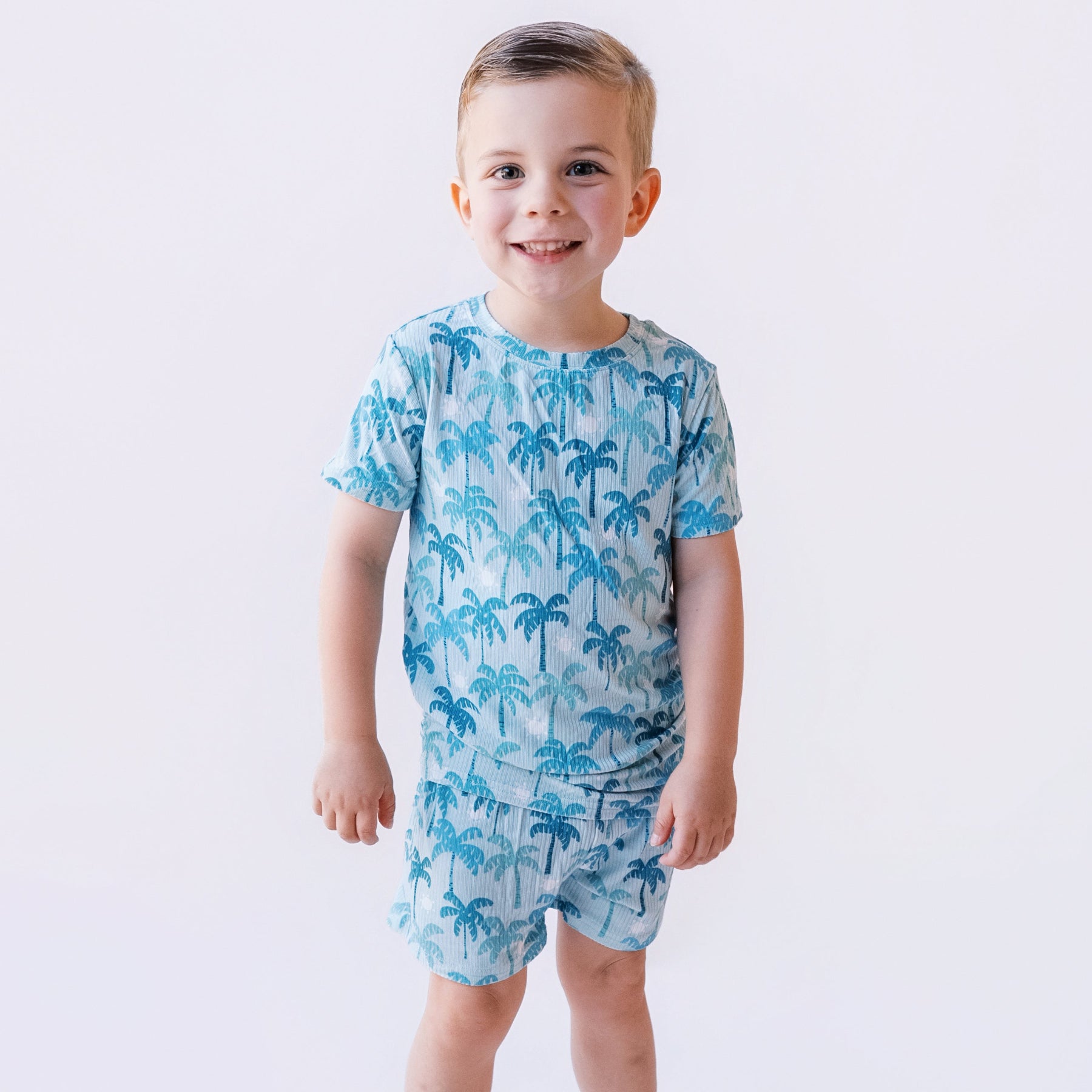 Child wearing a blue palm tree patterned pajama on a white background