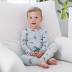 Child in light gray pajamas sitting on a white chair with a plant in the background