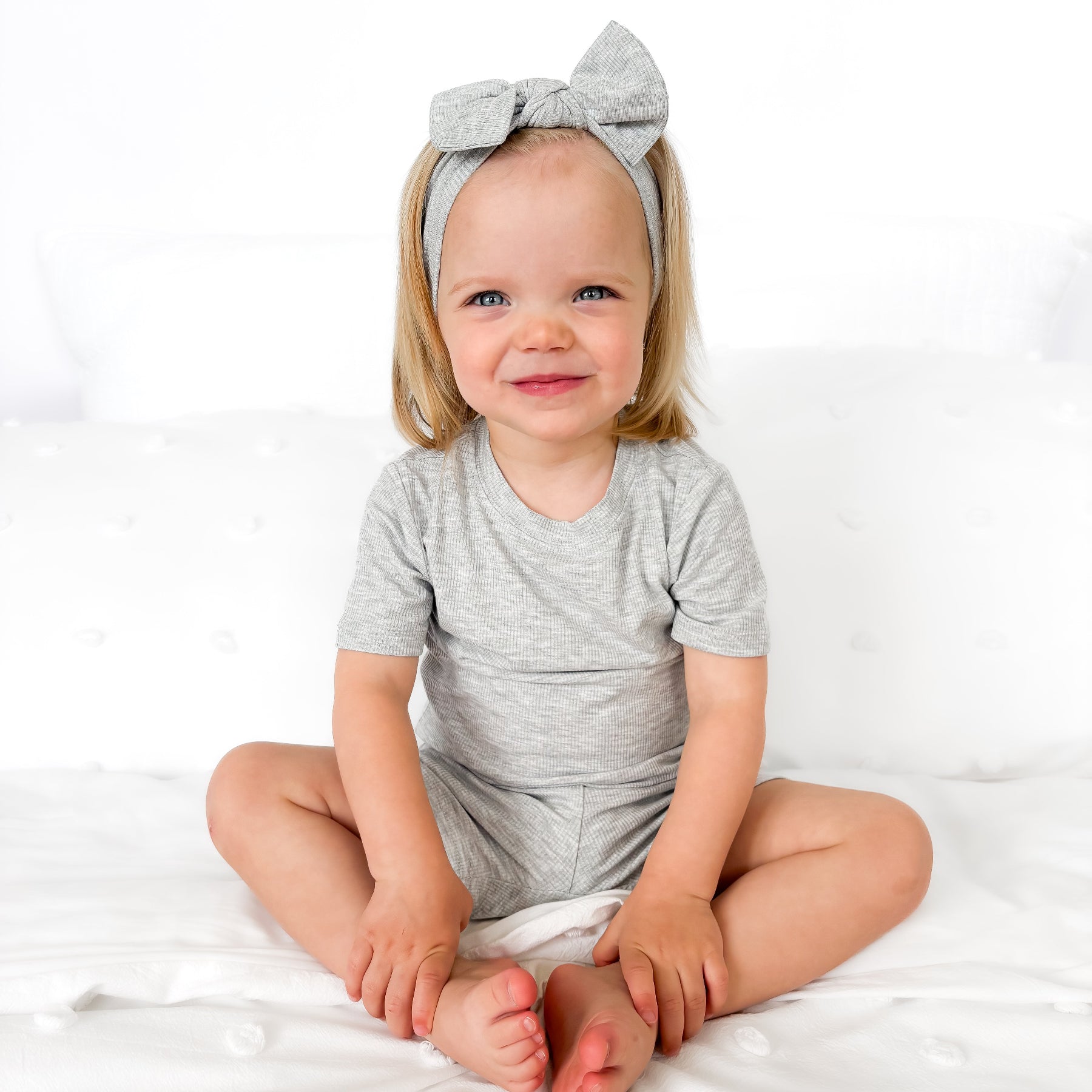 Child wearing a gray short pajamas with a matching bow on a white background