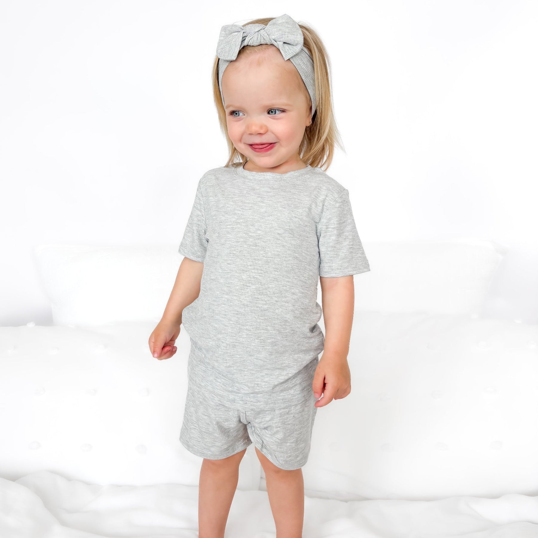 Child wearing a gray short pajamas with a matching bow on a white background