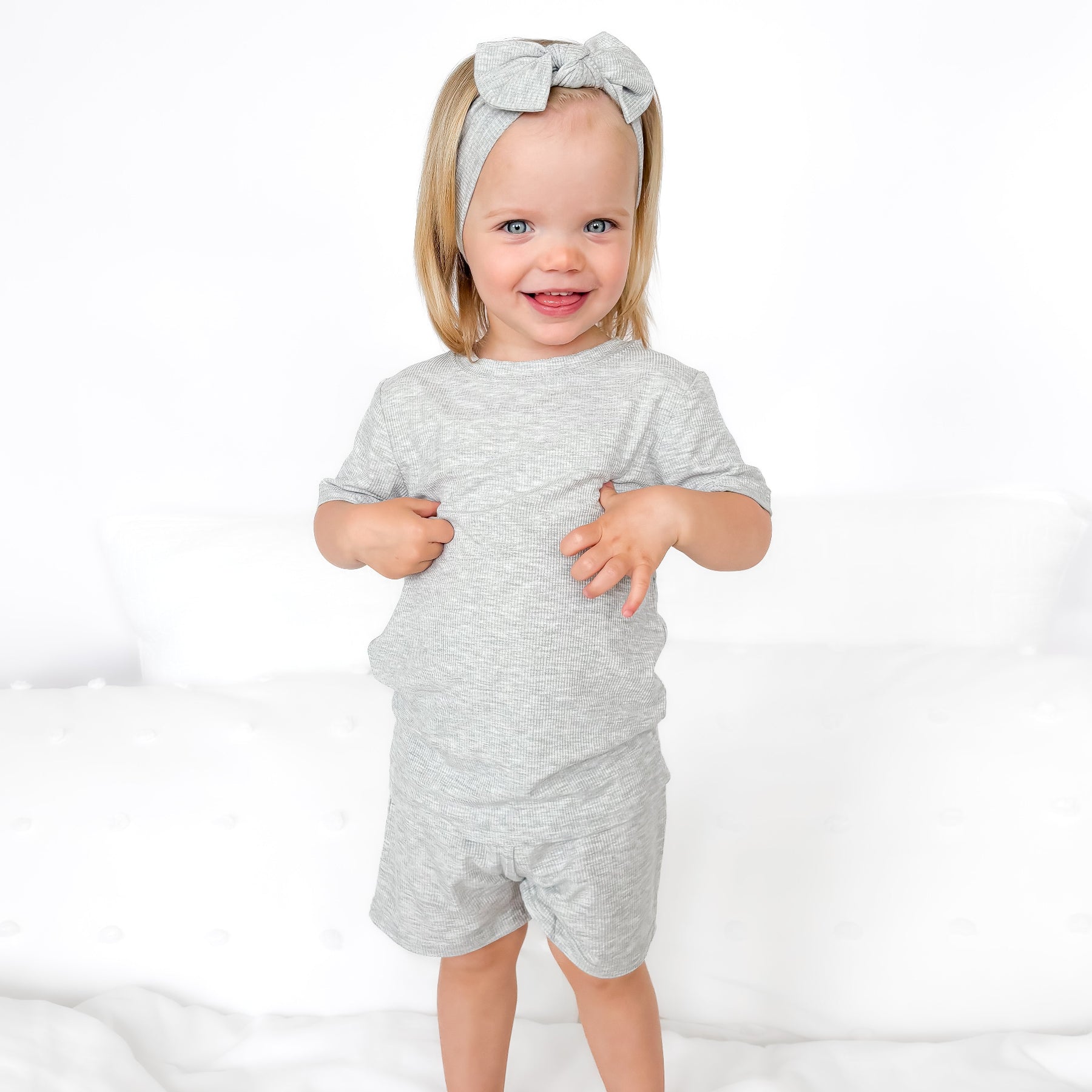 Child wearing a gray short pajamas with a matching bow on a white background