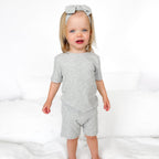 Child wearing a gray short pajamas with a matching bow on a white background