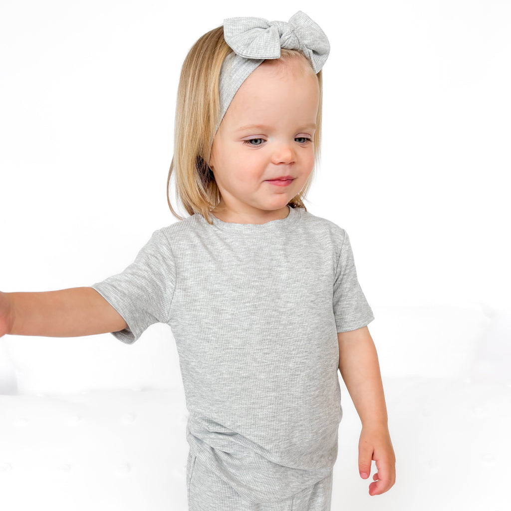 Child wearing a gray short pajamas with a matching bow on a white background