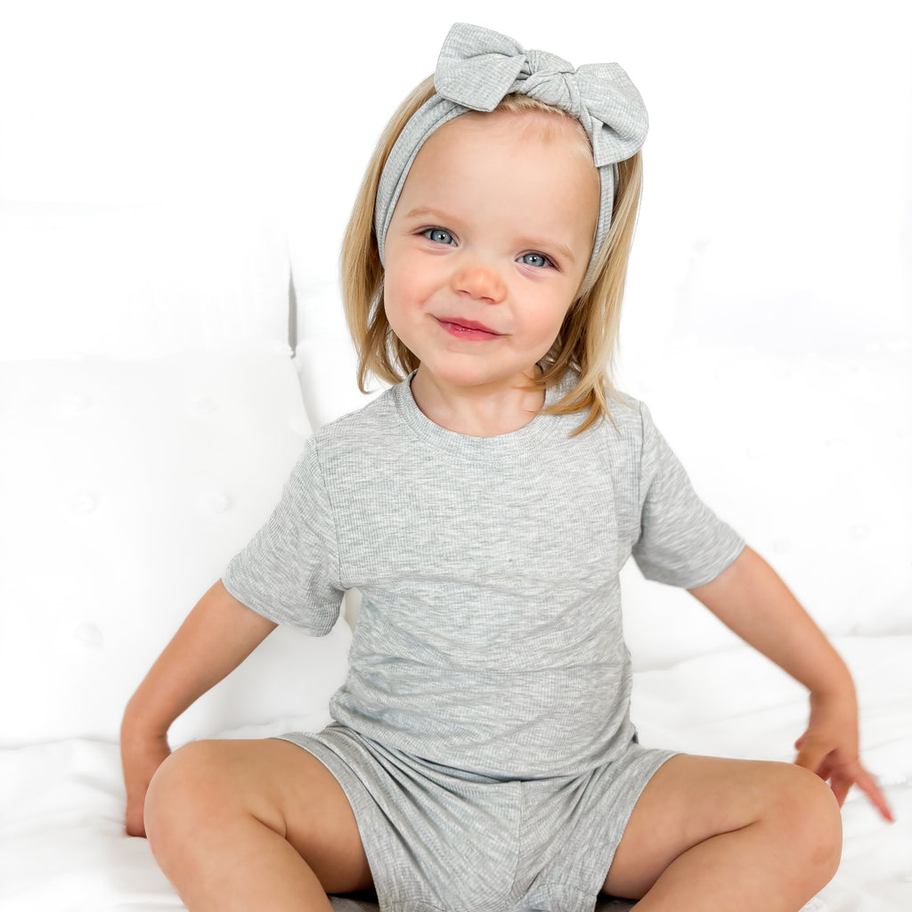 Child wearing a gray short pajamas with a matching bow on a white background