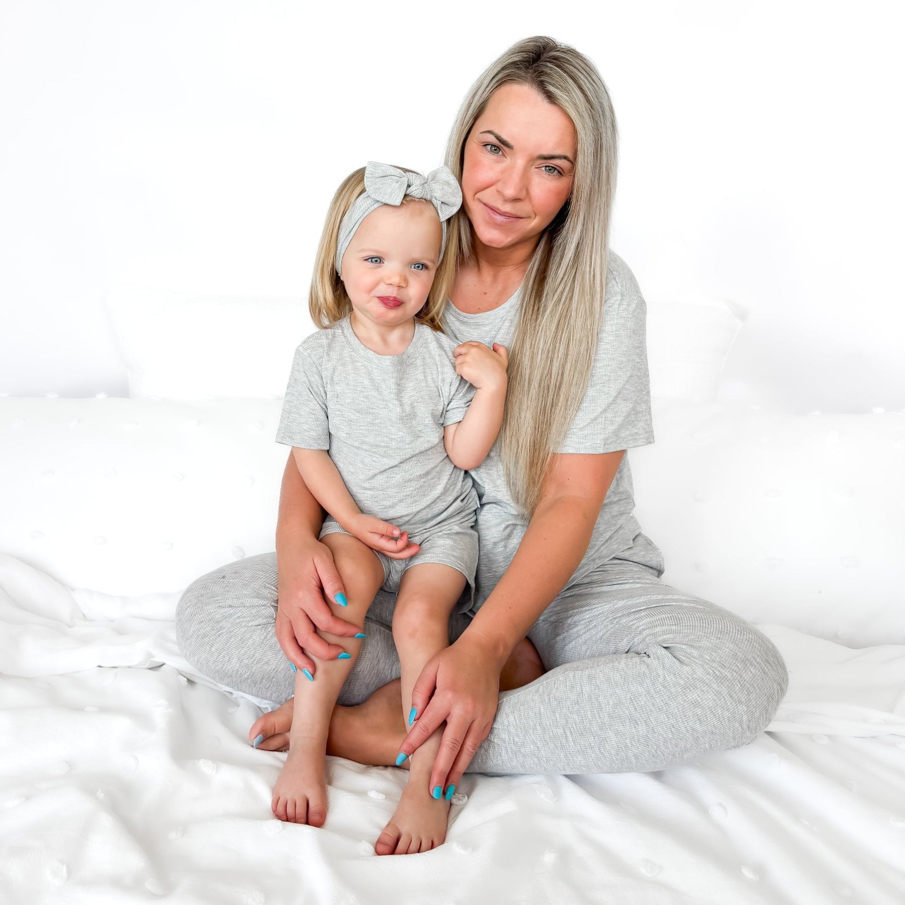 Woman and child wearing matching gray pajama sets on a white background