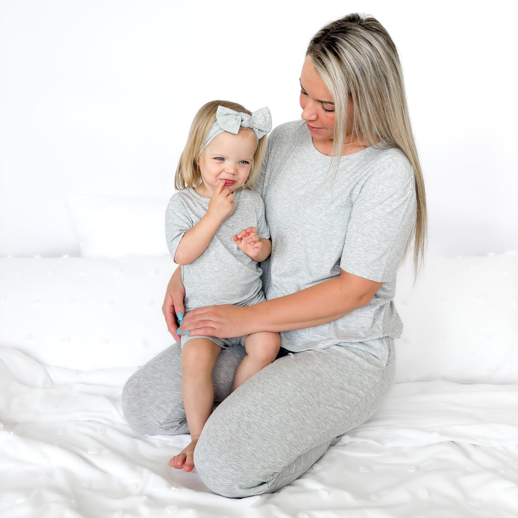Woman and child wearing matching gray pajama sets on a white background