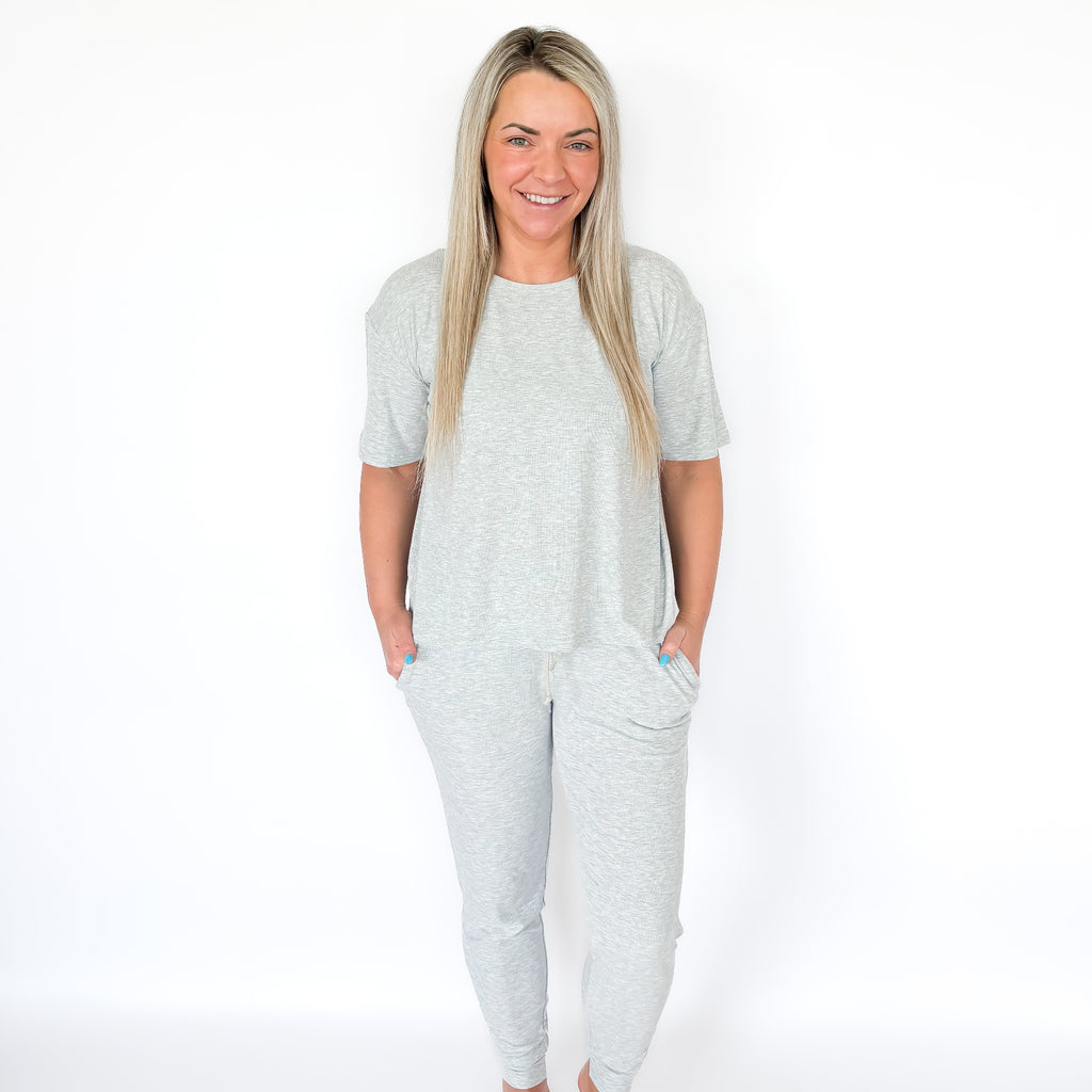 Woman wearing a light gray pajama set on a white background