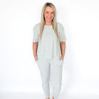 Woman wearing a light gray pajama set on a white background