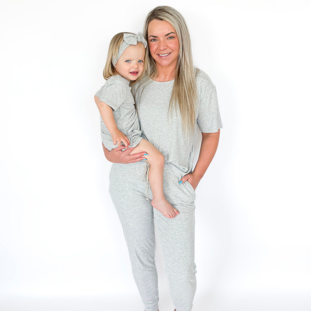 Woman and child wearing matching gray pajama sets on a white background