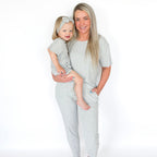 Woman and child wearing matching gray pajama sets on a white background