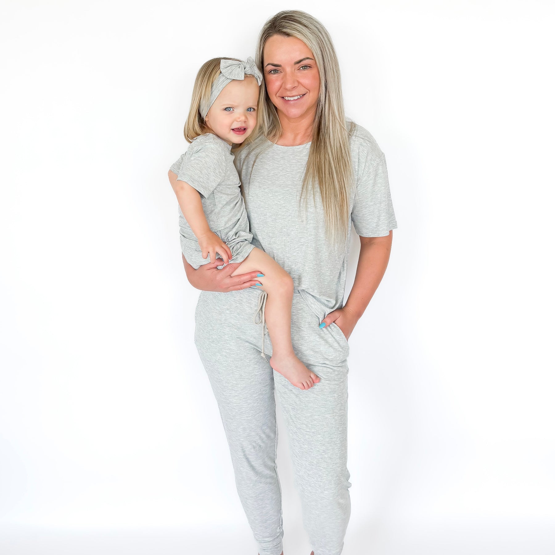 Woman and child wearing matching gray pajama sets on a white background