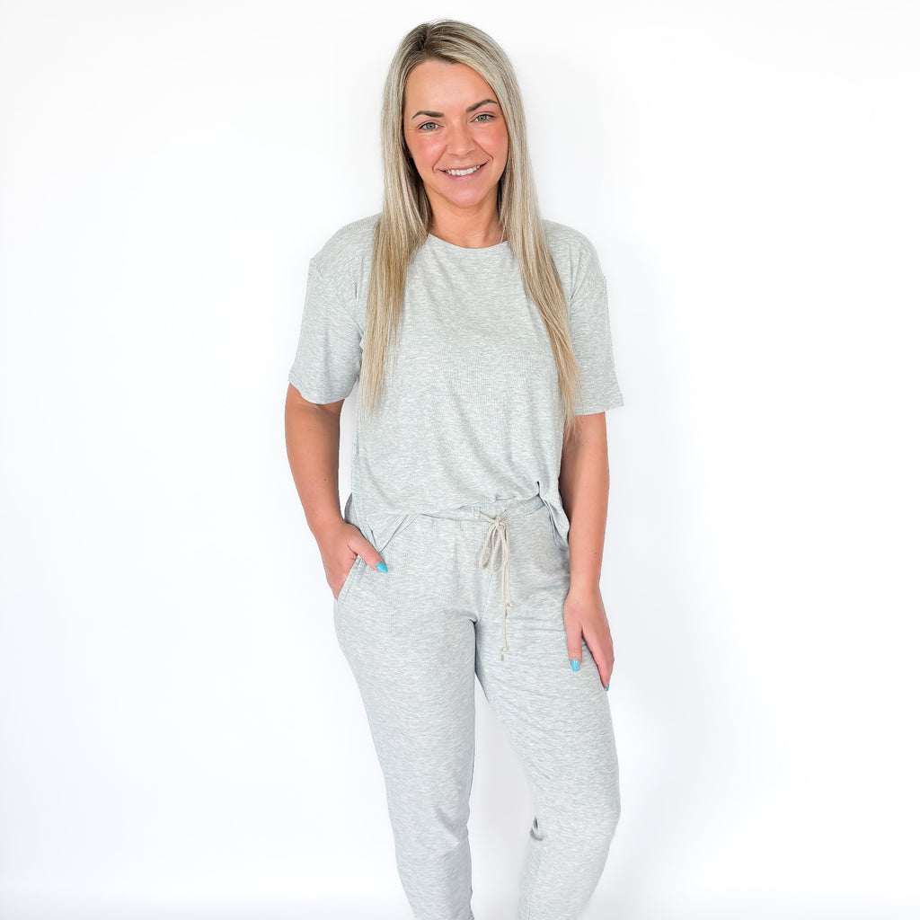 Woman wearing a light gray pajama set on a white background
