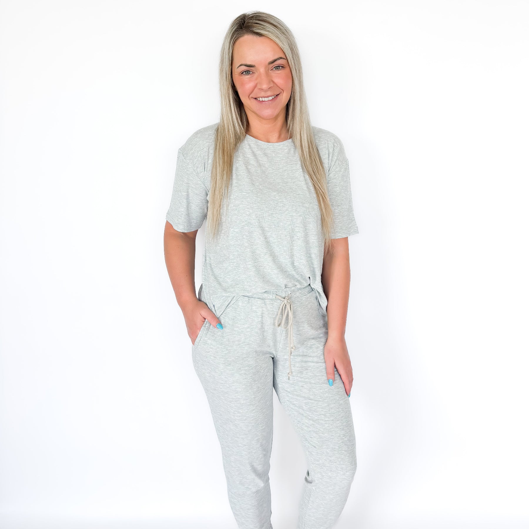 Woman wearing a light gray pajama set on a white background