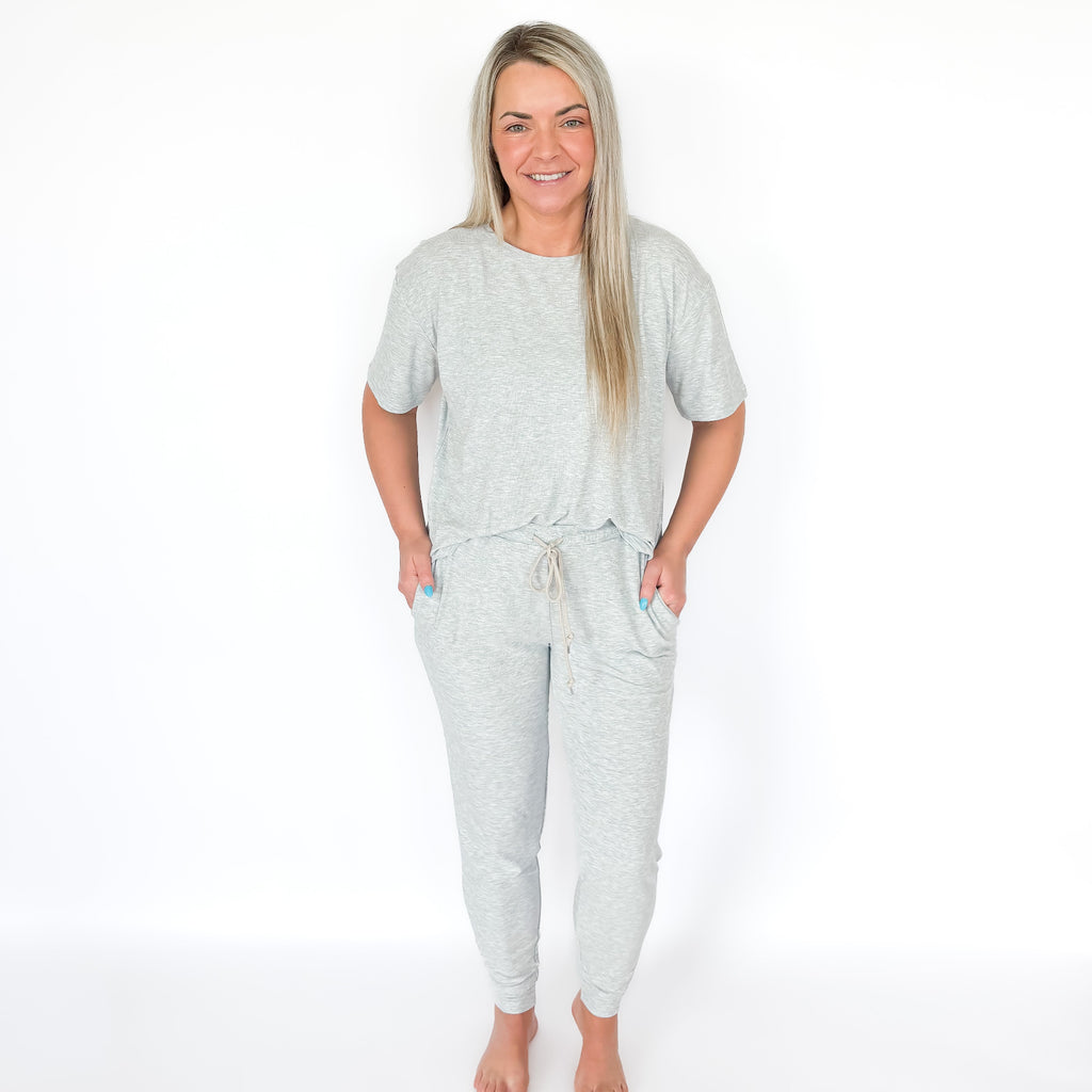 Woman wearing a light gray pajama set on a white background