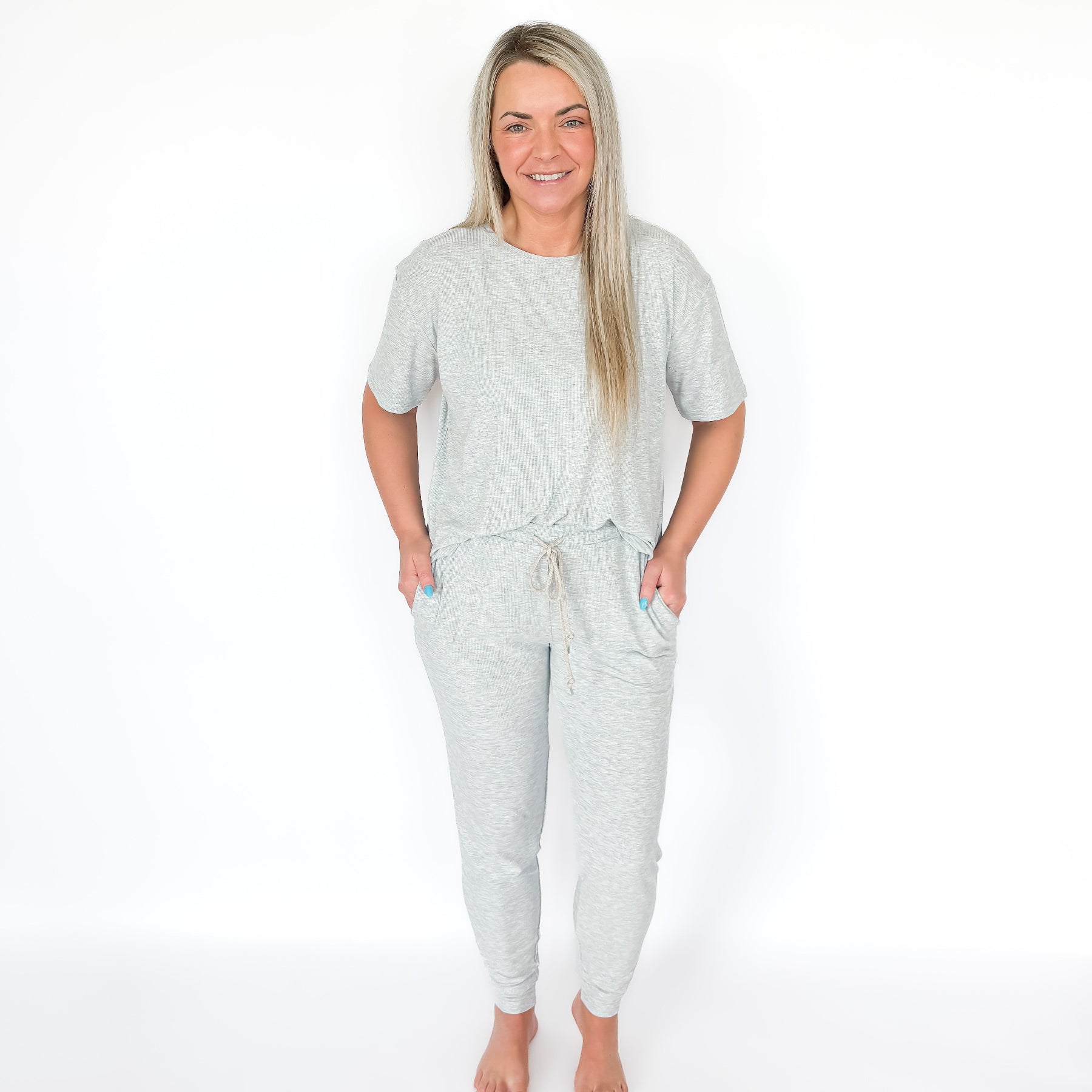Woman wearing a light gray pajama set on a white background