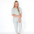 Woman wearing a light gray pajama set on a white background