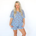 Woman wearing a blue checkered pajama set with red cherries pattern on a white background