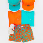 Set of orange and teal shirts with matching shorts and hats on a white background