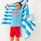 Child wearing a blue 'USA' t-shirt with checkered shorts, holding a striped towel on a white background