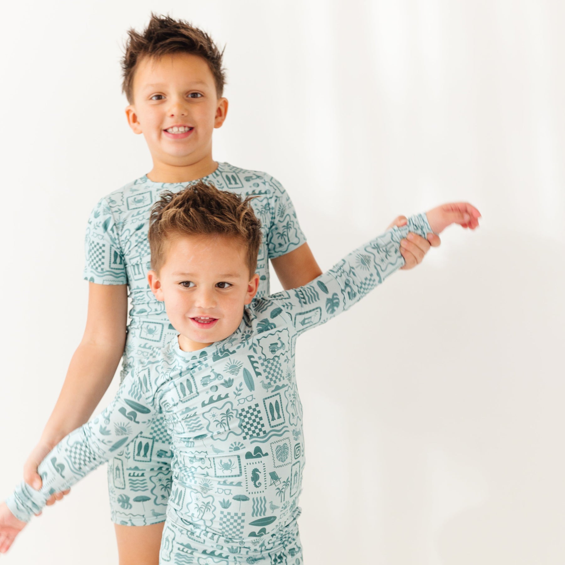 Two children wearing matching pajamas standing on a white background