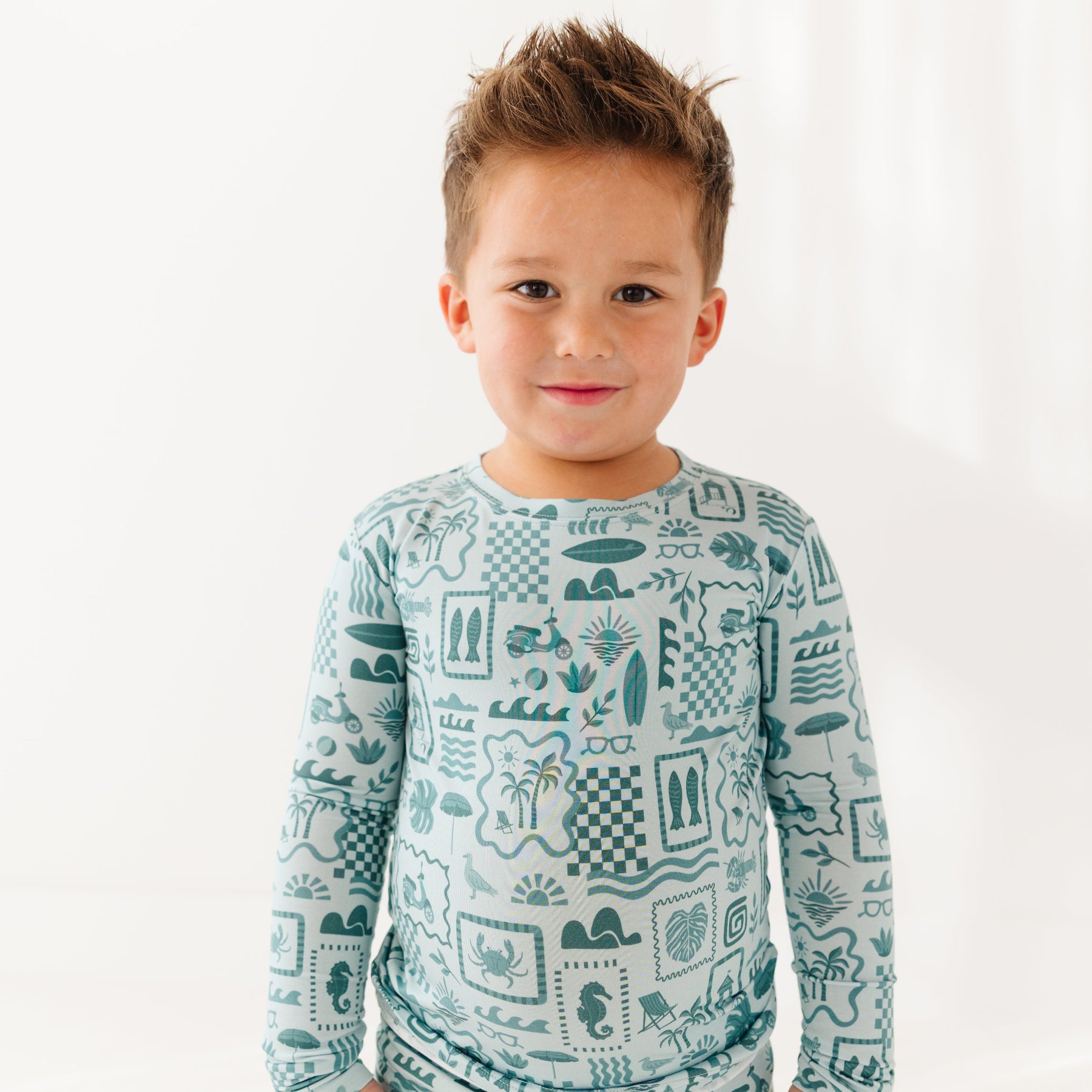 Child wearing a blue summer-patterned pajama set on a white background