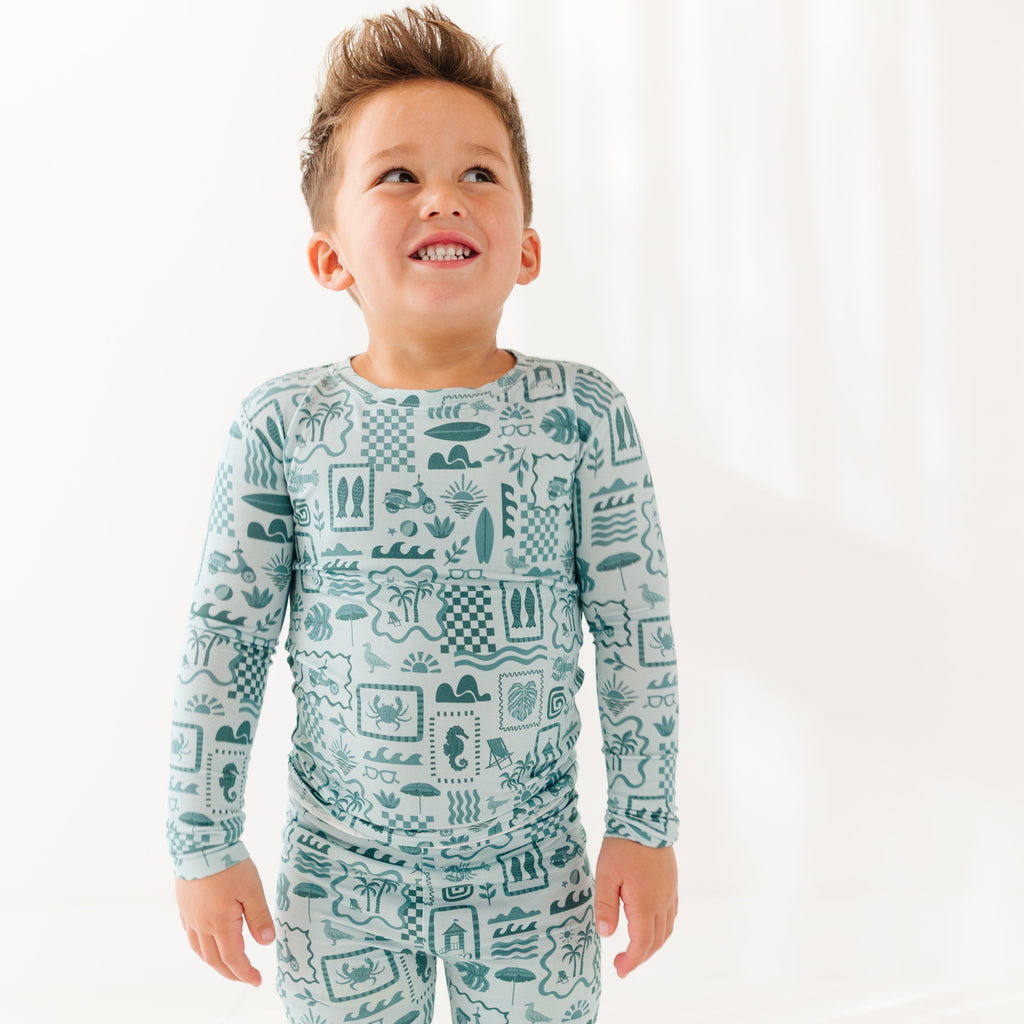 Child wearing a blue summer-patterned pajama set on a white background