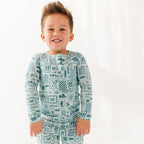 Child wearing a blue summer-patterned pajama set on a white background