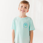 Child wearing a light blue t-shirt with a palm tree logo design on a white background