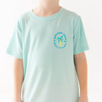 Child wearing a light blue t-shirt with a palm tree logo design on a white background