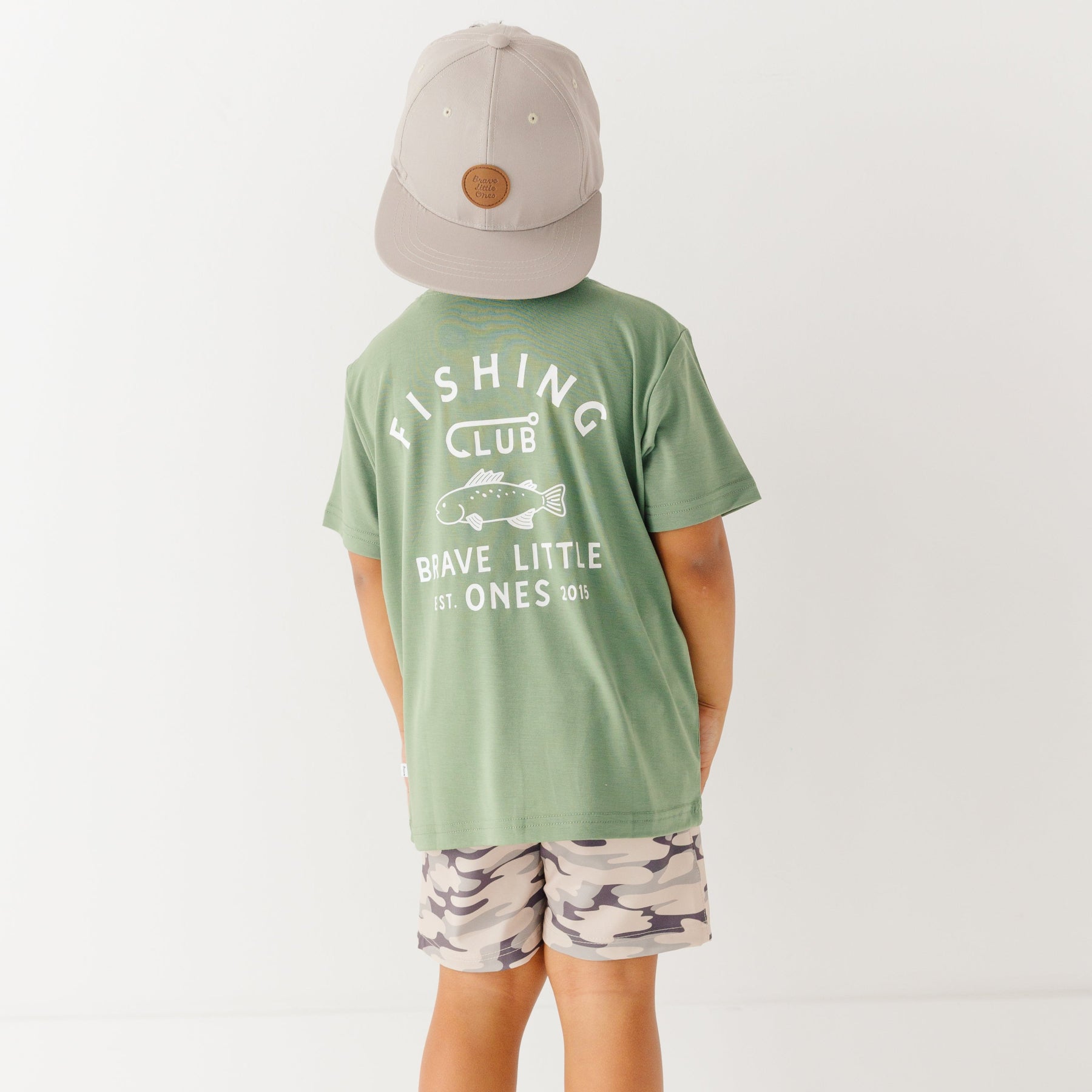Child wearing a green t-shirt with 'Fishing Club' text and camouflage shorts on a white background