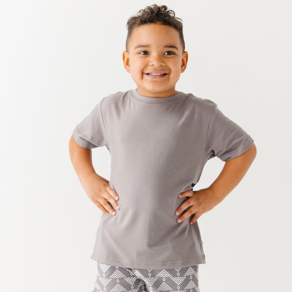 Child wearing a gray t-shirt and geometric-patterned shorts on a white background